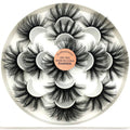 Dramatic long black faux mink-style false eyelashes on a circular tray with label.
