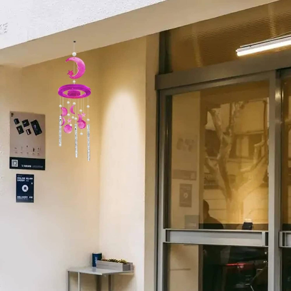 Pink moon and star wind chime hanging by an indoor window
