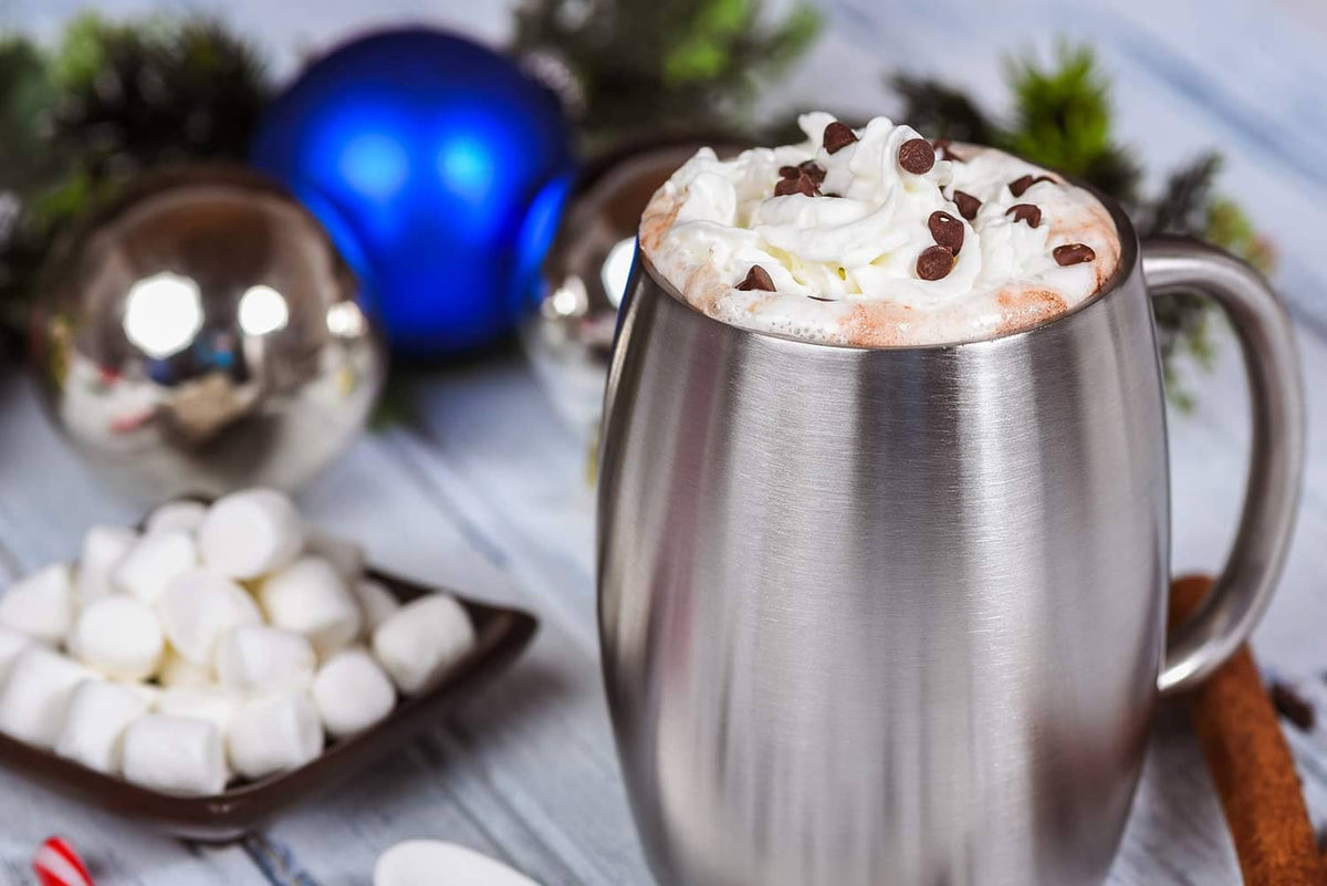 Stainless steel insulated coffee mug topped with whipped cream and cinnamon garnish