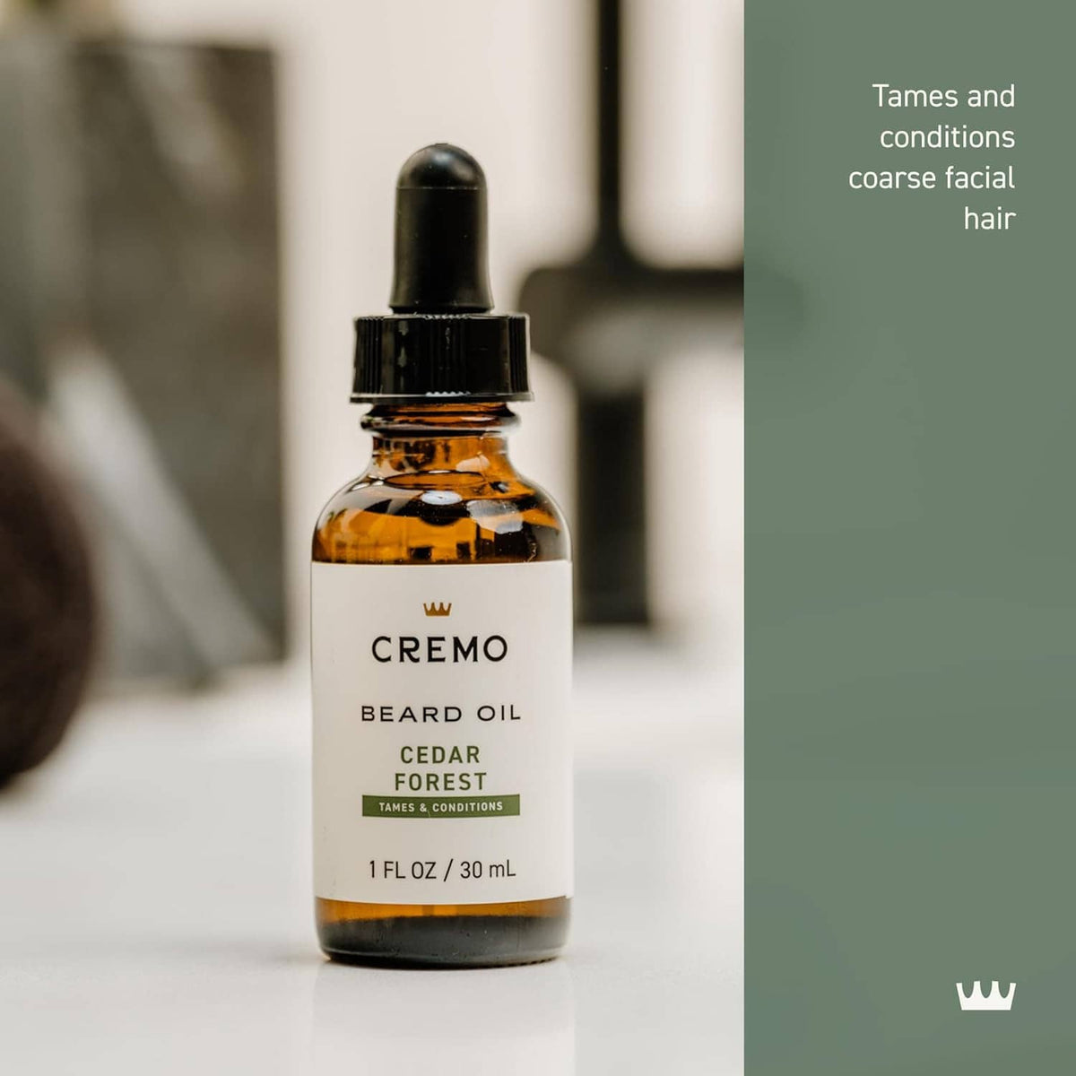 Cremo beard oil bottle close-up with amber glass, black dropper cap and white label