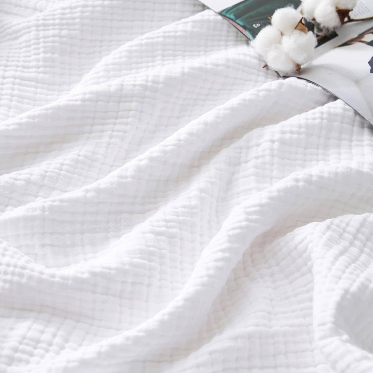 White 4-layer cotton muslin blanket, textured weave close-up with folded edge