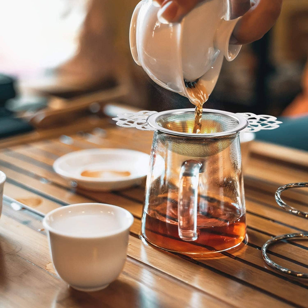 Mesh tea infuser over drip bowl during brewing, with tea pouring