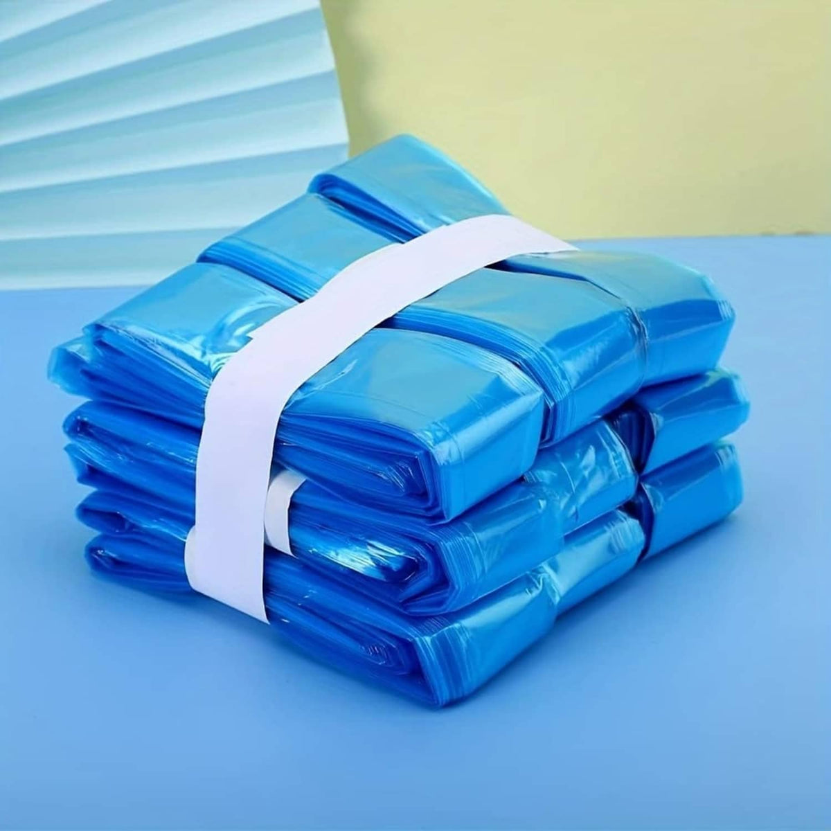Rolled blue cat litter refill bags stacked with a white tie strap across the bundle.