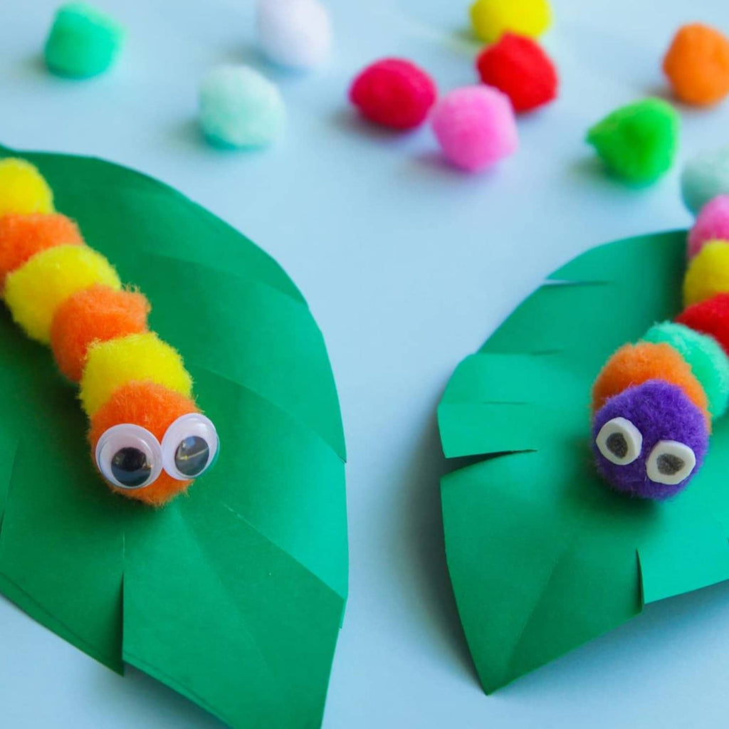 Two green craft cones with googly eyes and multicolor pom pom decorations