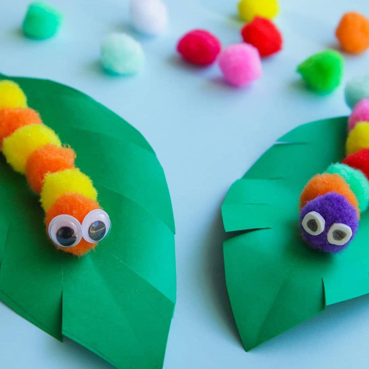 Two green craft cones with googly eyes and multicolor pom pom decorations