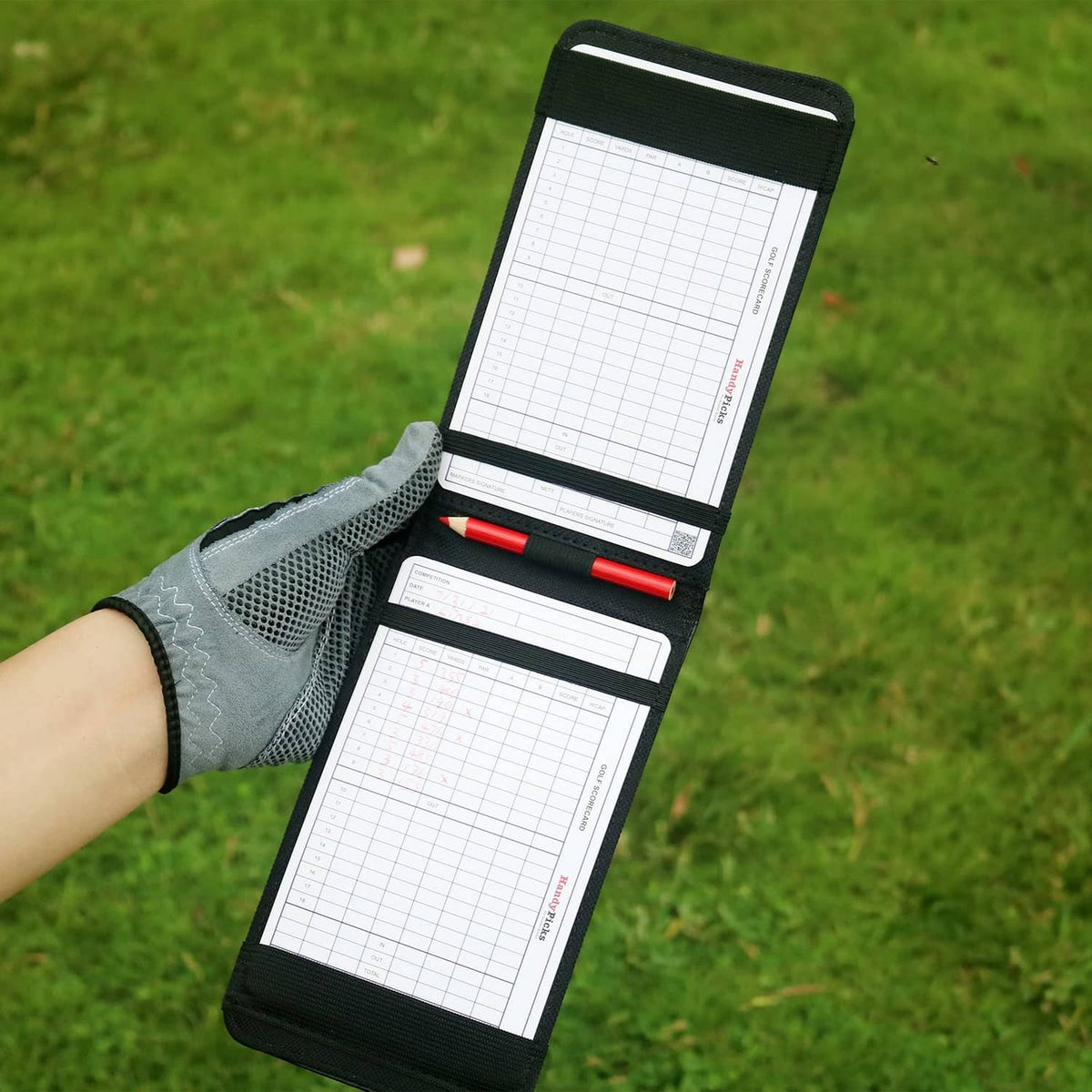 Black leather golf scorecard holder open with multiple scorecard sheets and red pen
