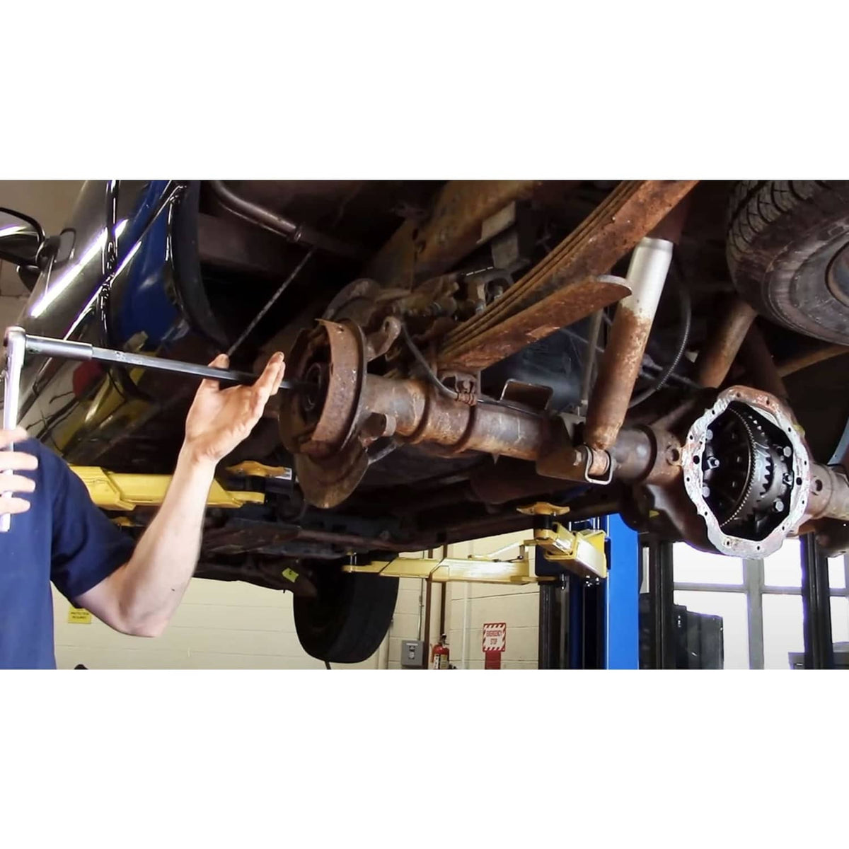 Mechanic applying differential wrench to axle housing, black socket head and red grip
