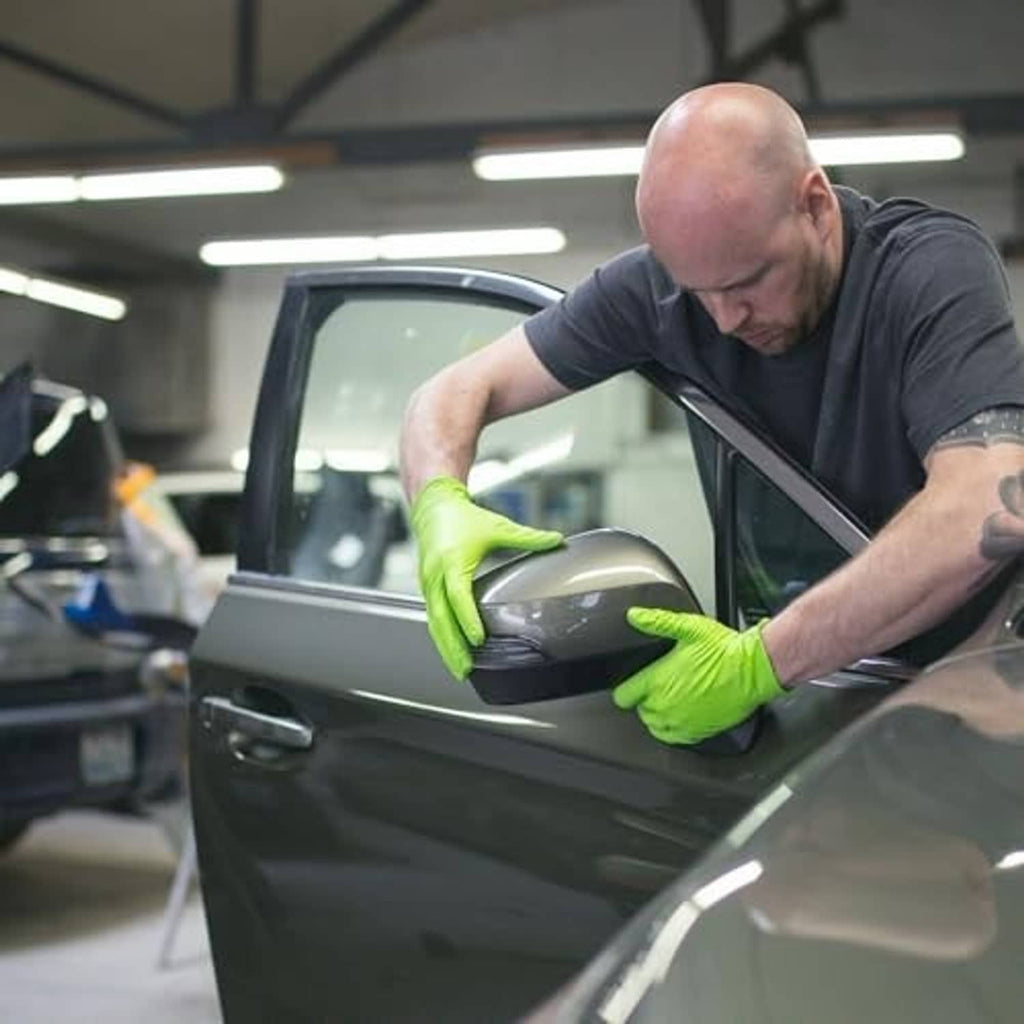 Pair of green nitrile gloves with textured grip handling car door