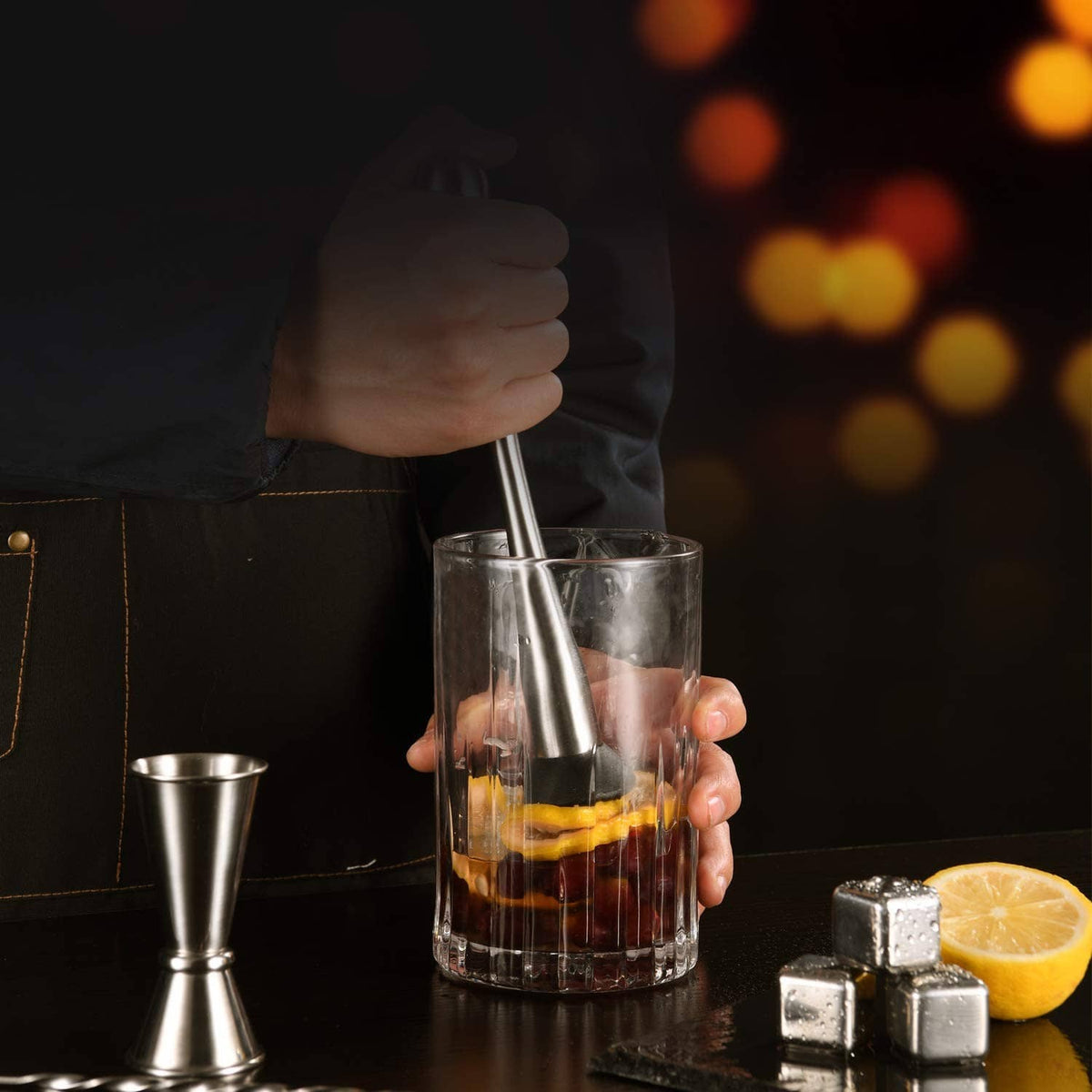 Stainless steel muddler pressing in a drink glass with black base