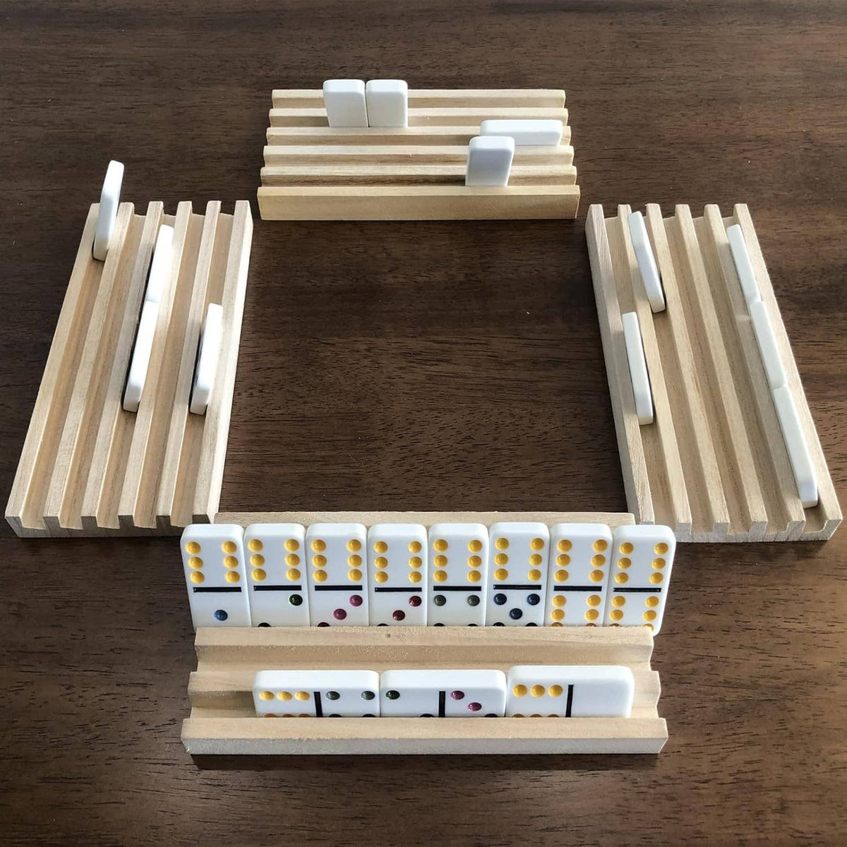 Wooden U-shaped domino rack with three slatted arms and white domino tiles in the center