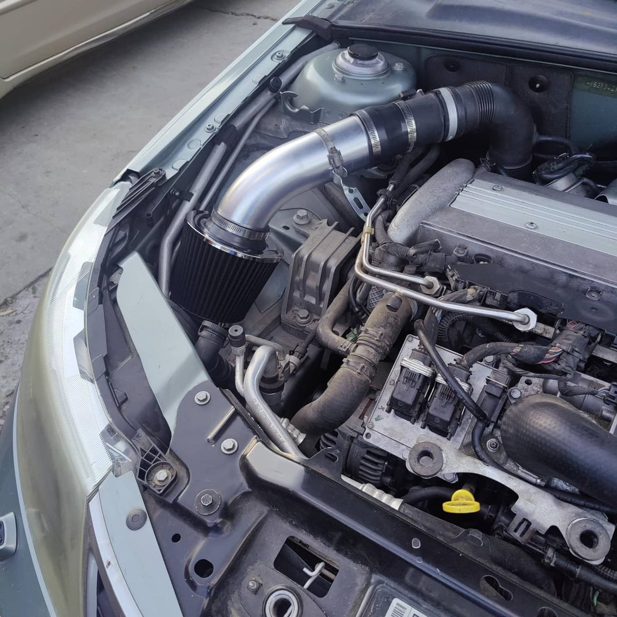 Engine bay with installed cold air intake kit featuring chrome tubing and cone air filters