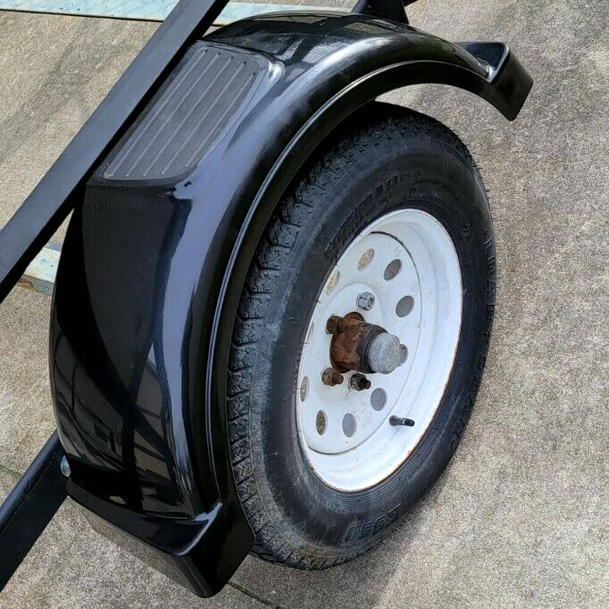 Black trailer fender mounted over a wheel with white rim