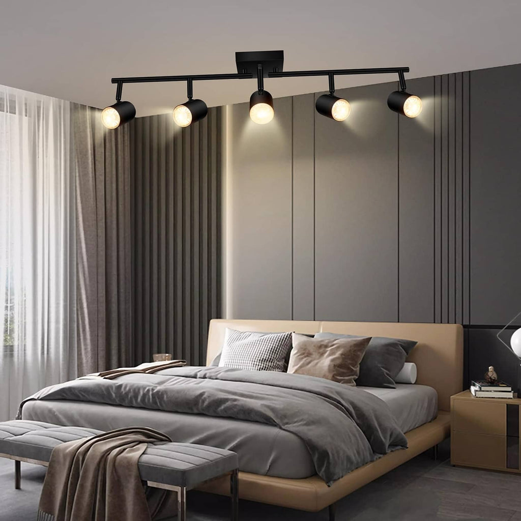 Black 5-light track lighting with cylindrical adjustable spotlights on a ceiling bar