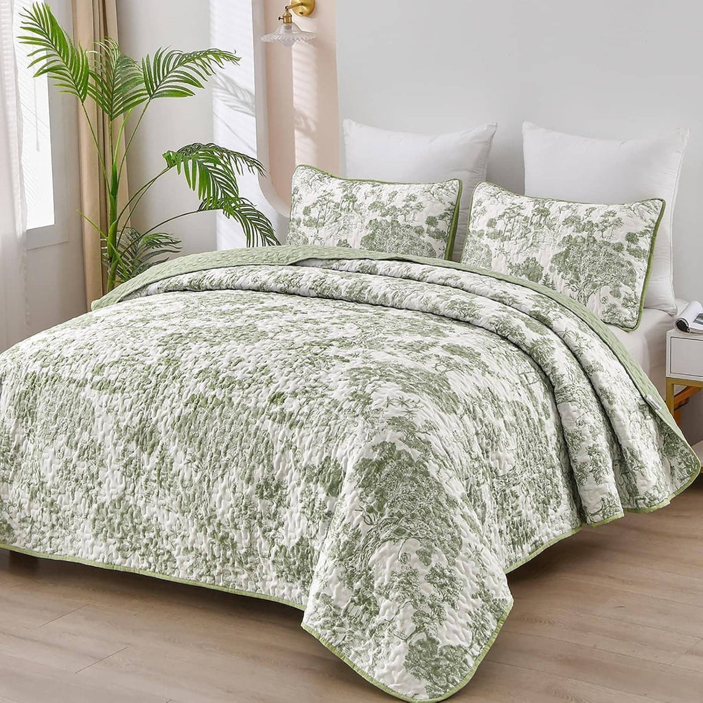 Sage green botanical quilt set with two matching pillow shams on a queen bed