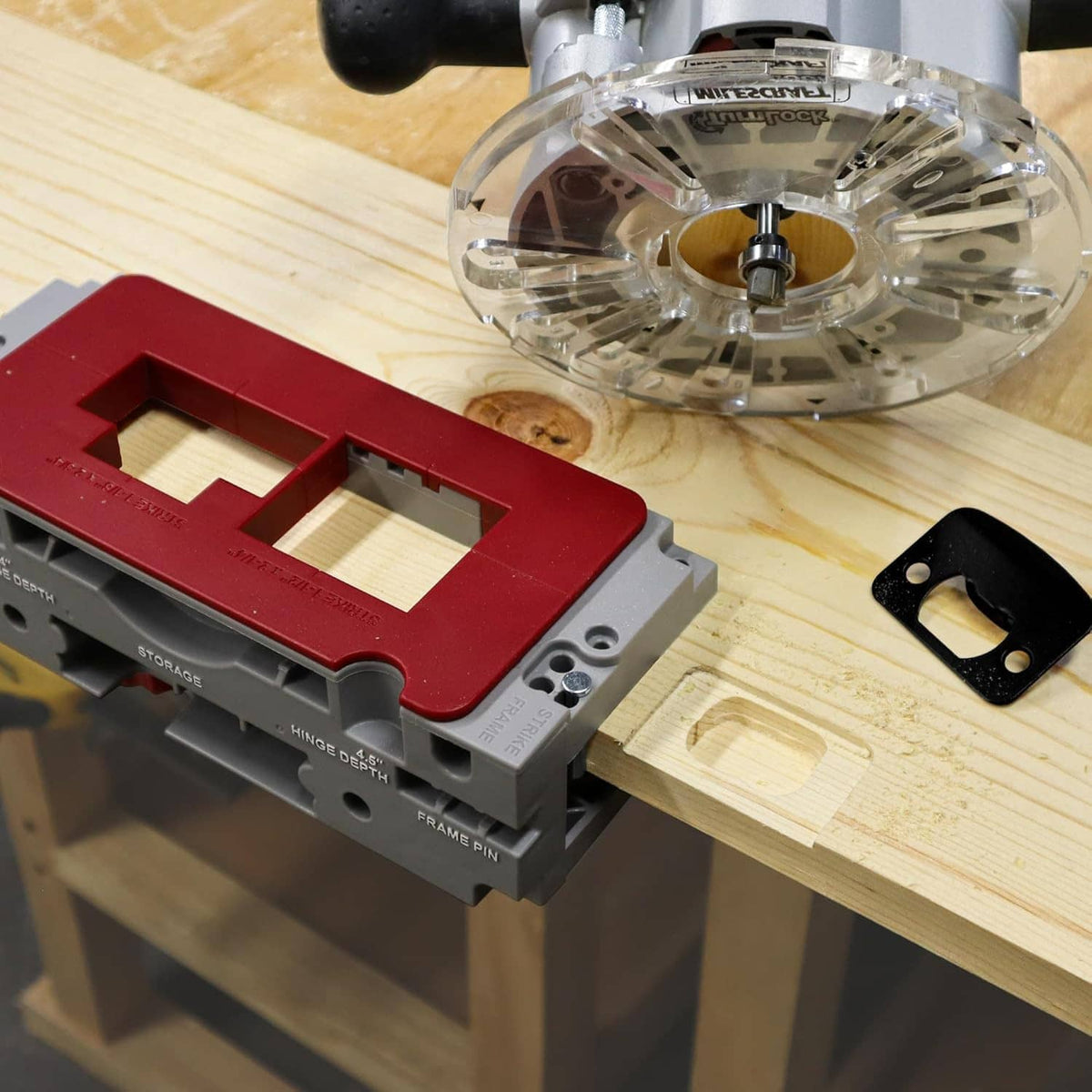 Door hinge mortising jig with red guide plate on wood, with clear router above