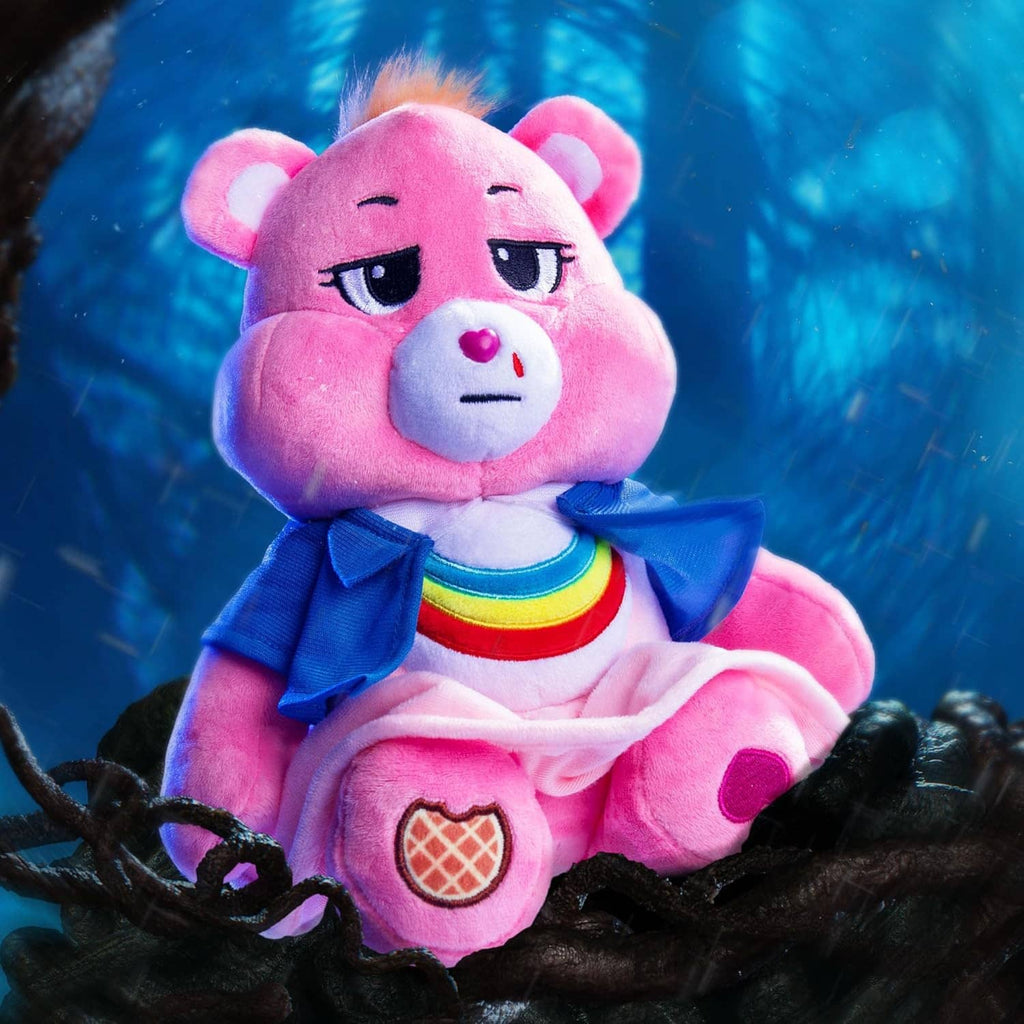 Close-up plush pink bear in blue scarf and rainbow-striped shirt, seated on dark fur