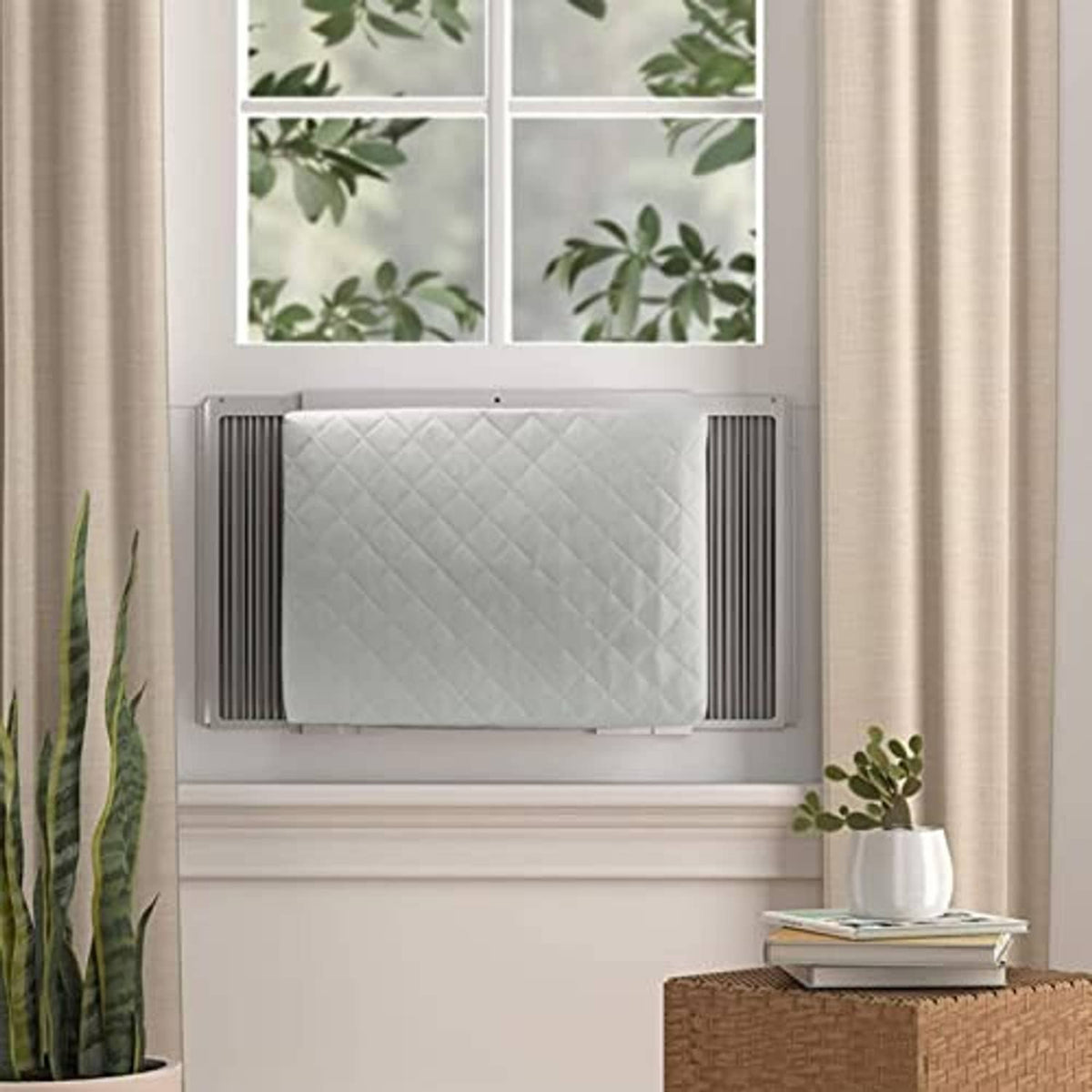 Grey quilted window AC unit cover installed inside a window opening.
