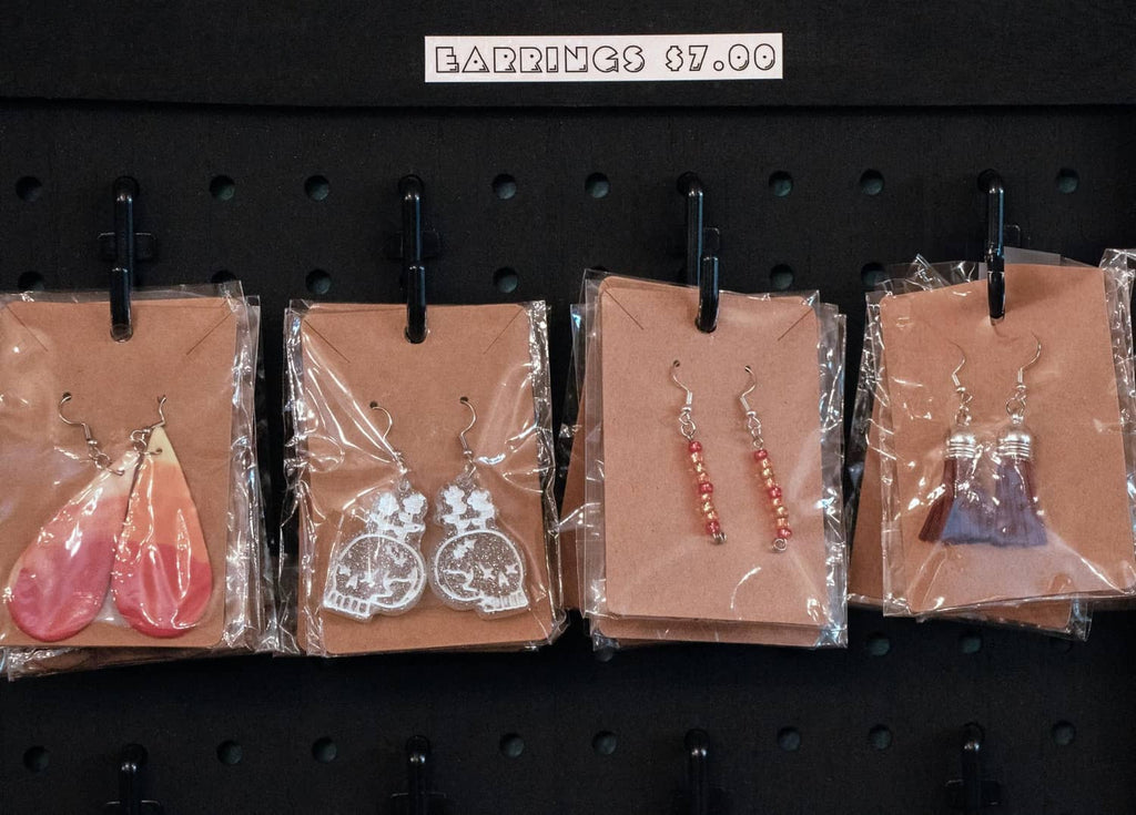 Earrings display cards with dangling earrings hanging on a black pegboard