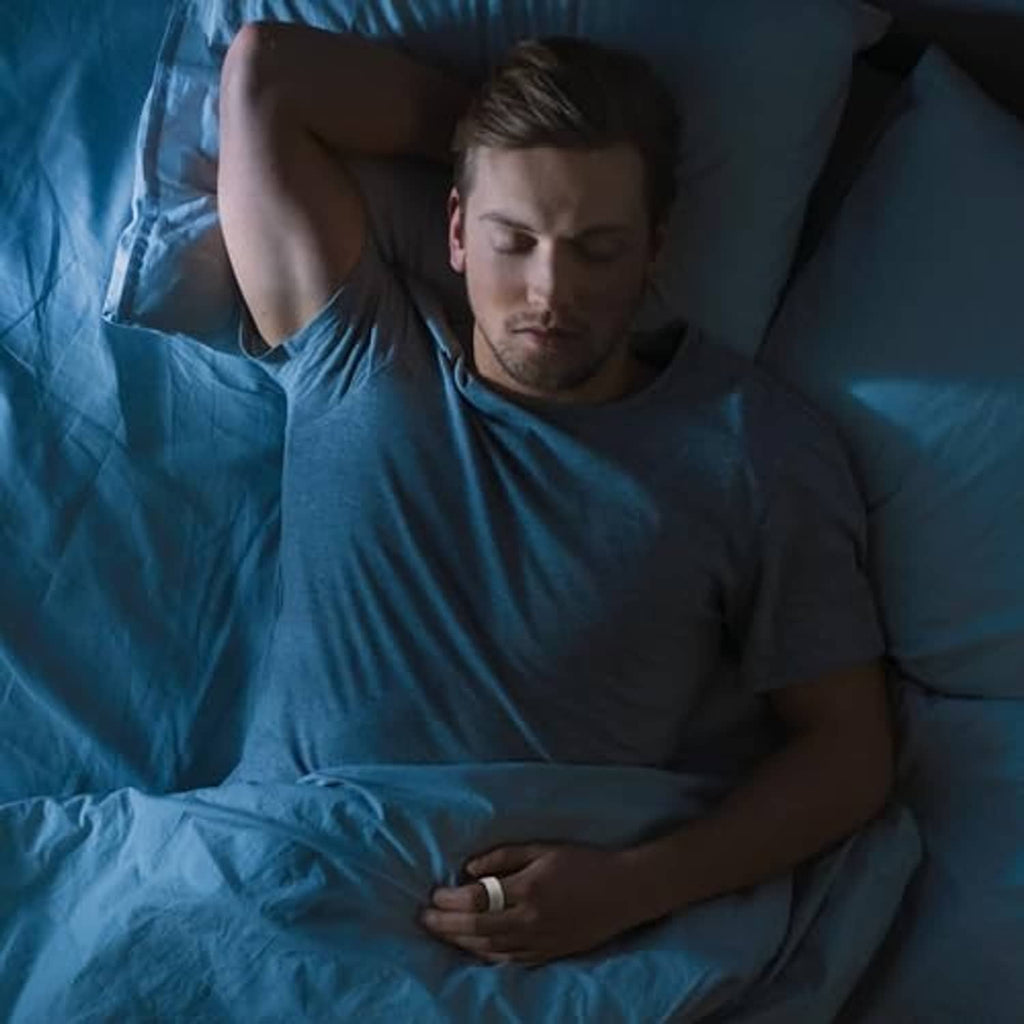 Man sleeping in bed while wearing a smart ring with a white protective case
