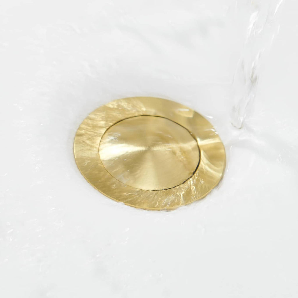 Brushed gold circular pop-up drain stopper cover with a center opening