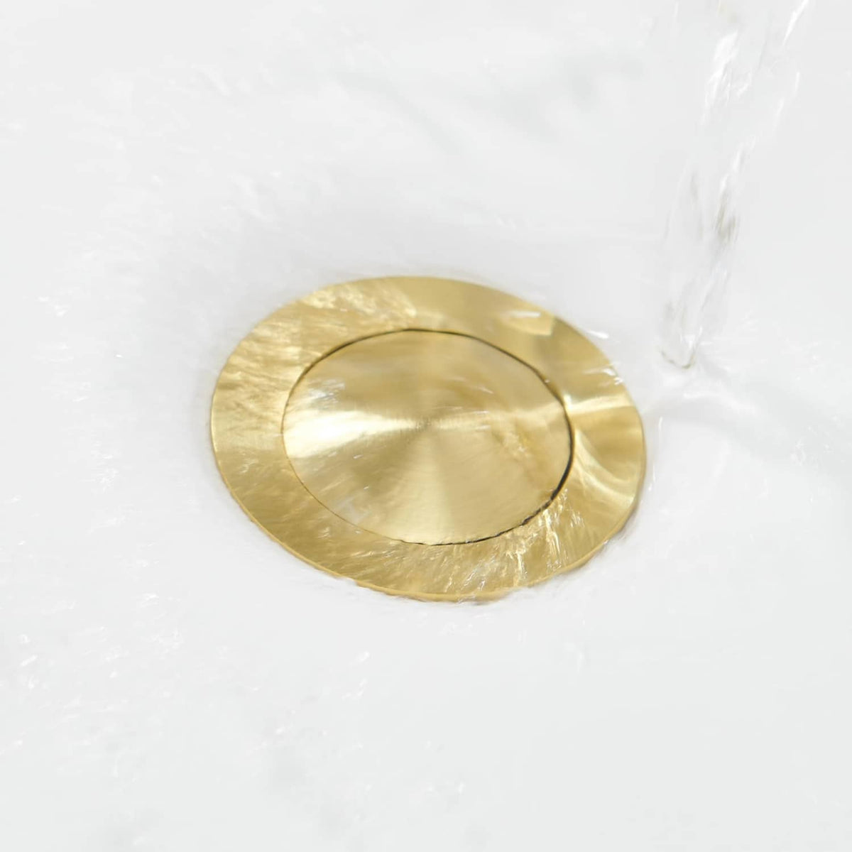 Brushed gold circular pop-up drain stopper cover with a center opening