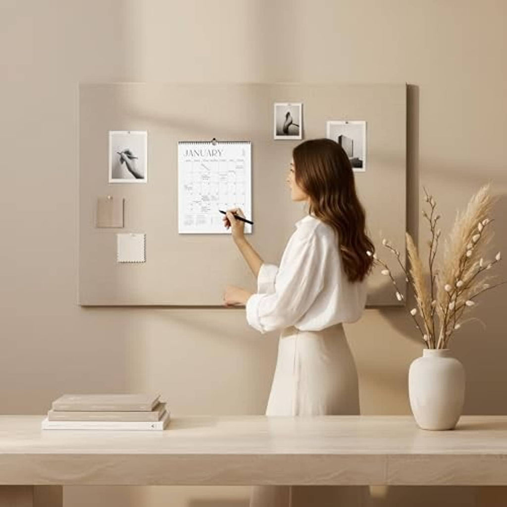 January wall calendar with spiral binding and date grid, pinned among framed photos