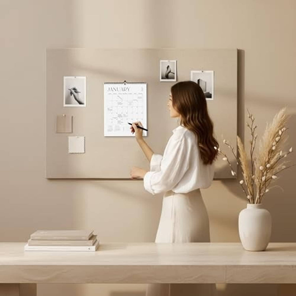 January wall calendar with spiral binding and date grid, pinned among framed photos