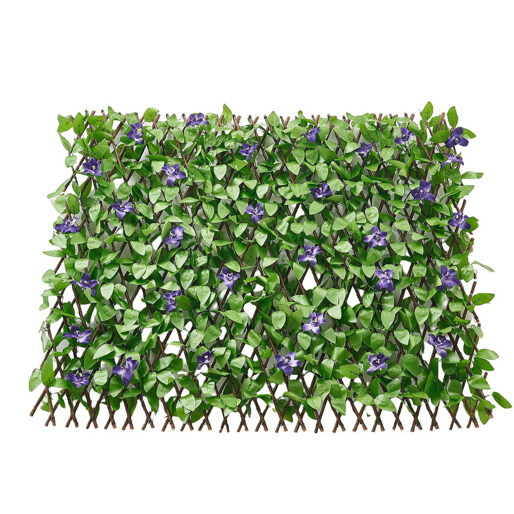 Dense green artificial ivy privacy screen with scattered purple flower clusters