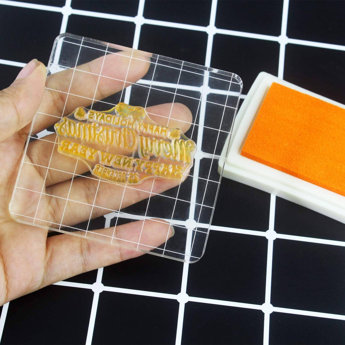 Clear acrylic stamp block with grid lines, holding an inked word design stamp