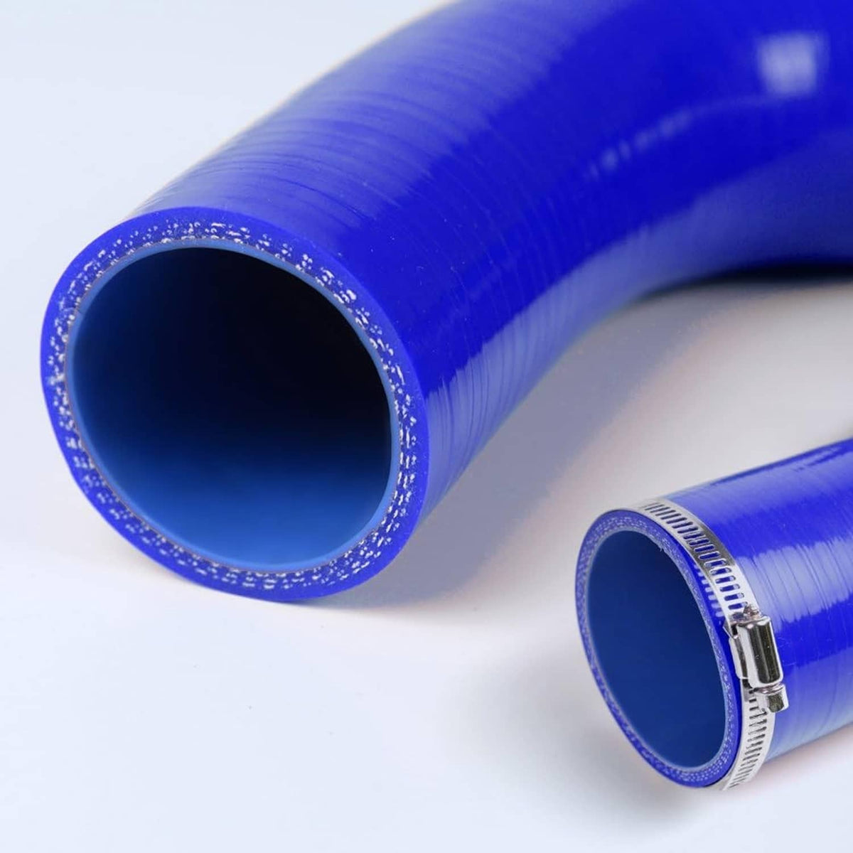Blue silicone radiator hoses with metal clamps, close-up of hose openings and edges.