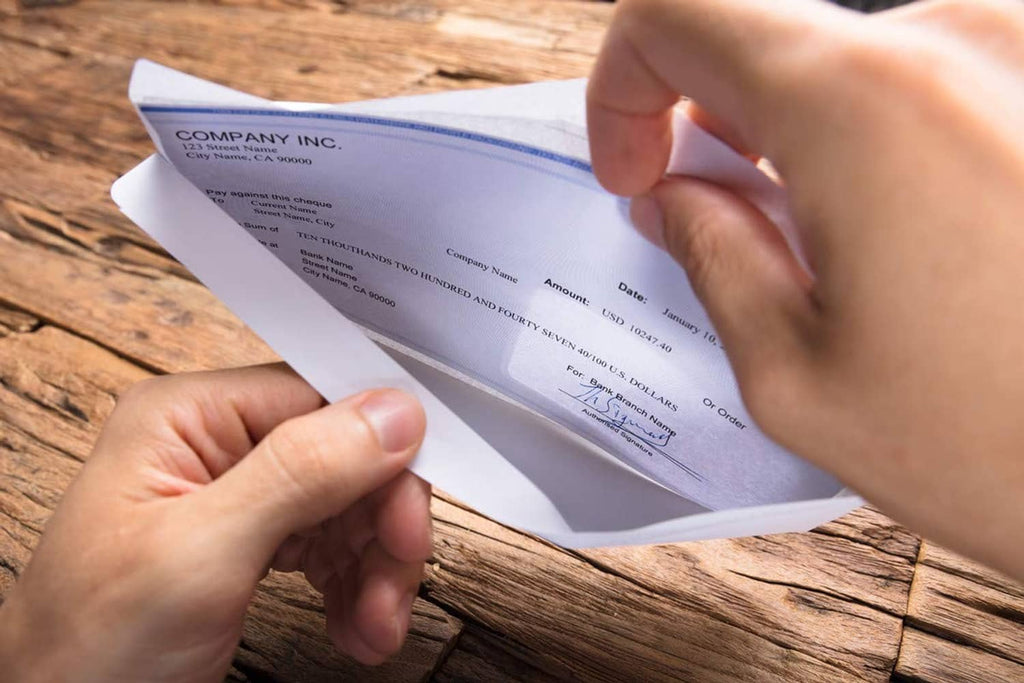 White double-window envelope being sealed by hand, adhesive flap visible