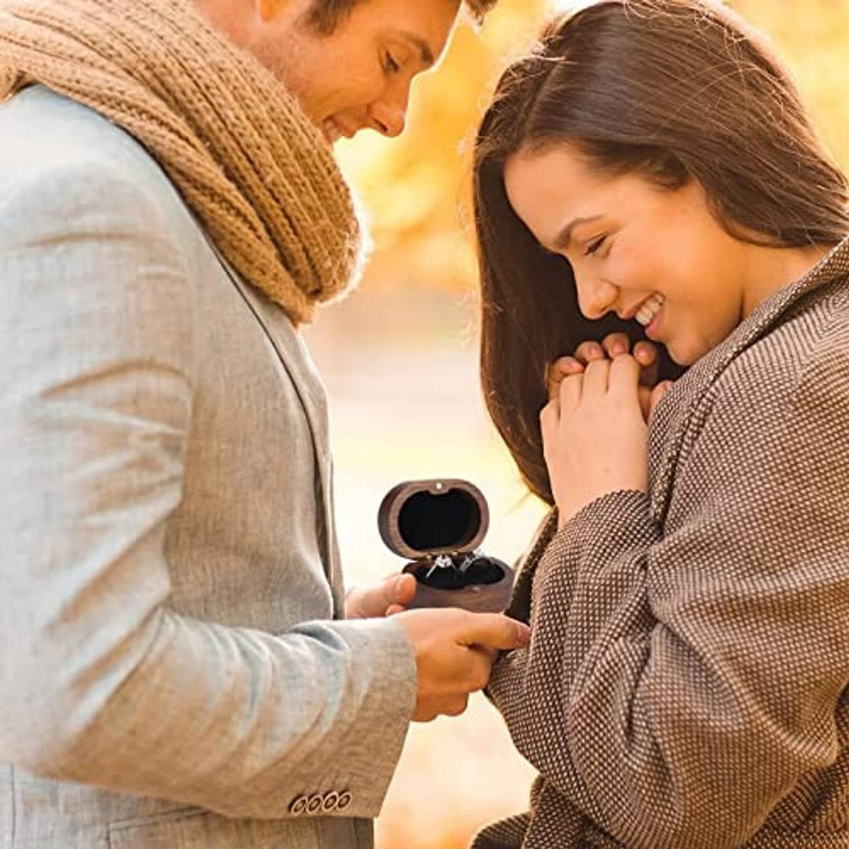Open wooden ring box in hands, showing two rings inside during proposal