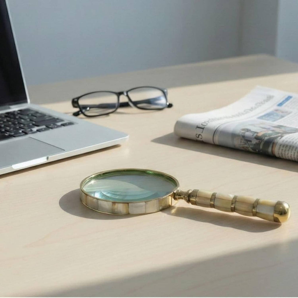 Mother-of-pearl magnifying loupe with gold frame and striped brass handle on desk