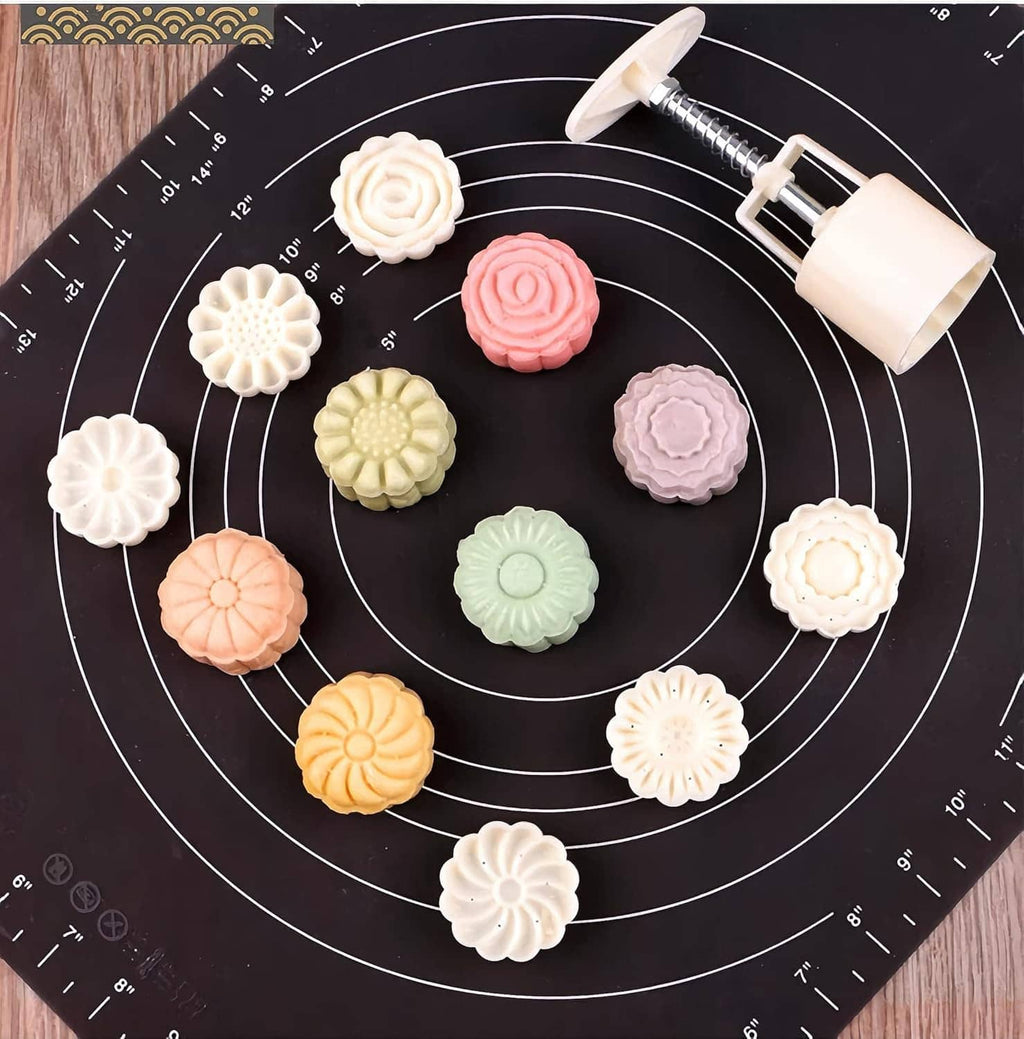 Hand-press moon cake moulds with pastel flower and spiral shapes on silicone mat