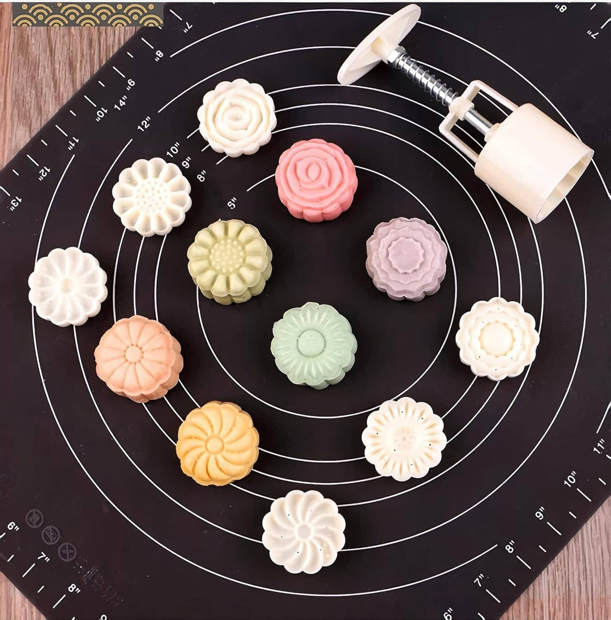 Hand-press moon cake moulds with pastel flower and spiral shapes on silicone mat