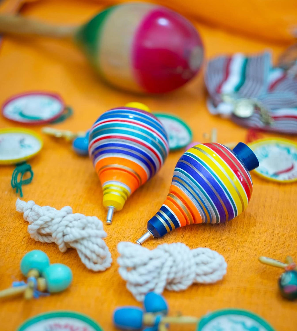 Two multicolor striped wooden spinning tops with metal tips and white rope cords