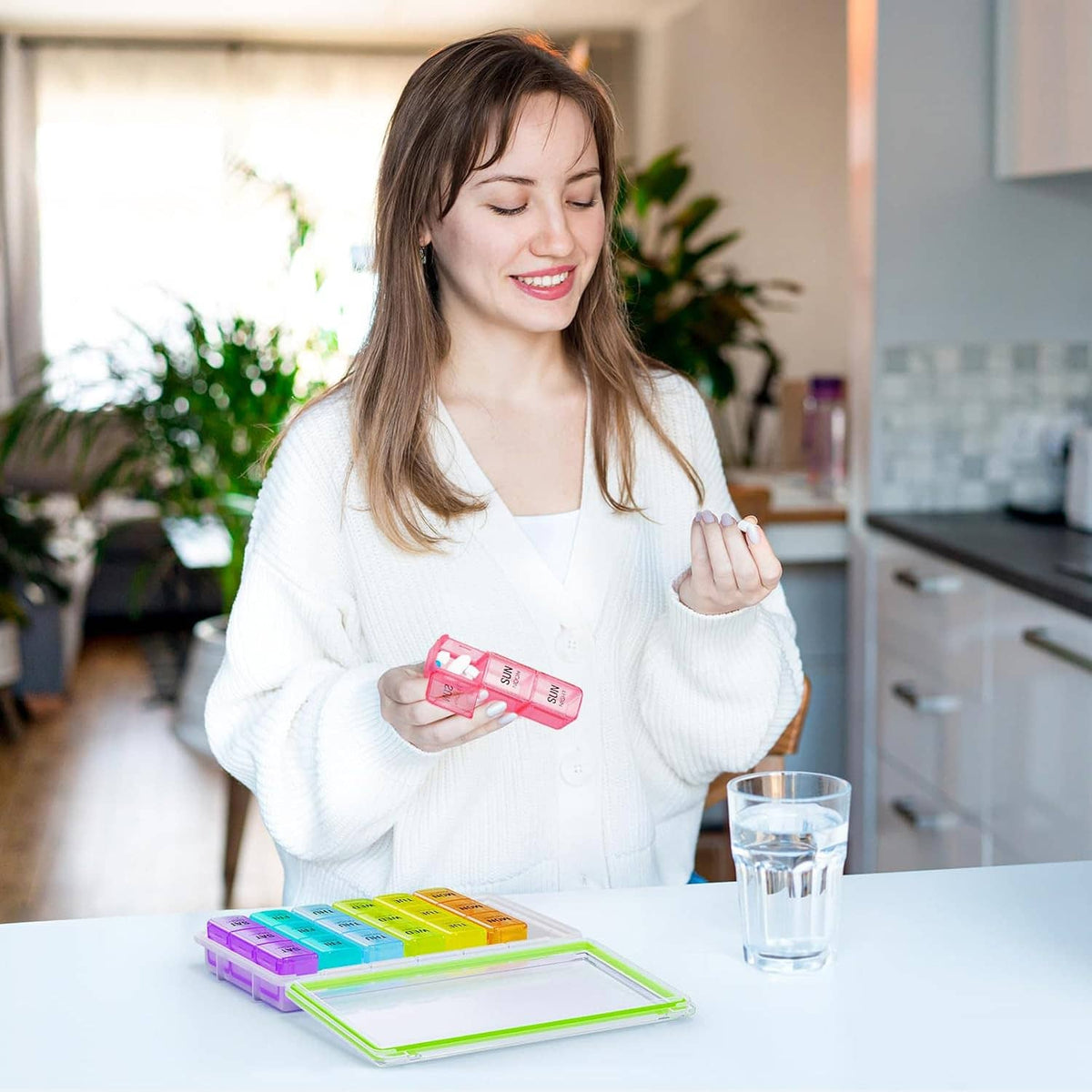 Person holding a weekly pill organizer while placing pills into colorful compartments