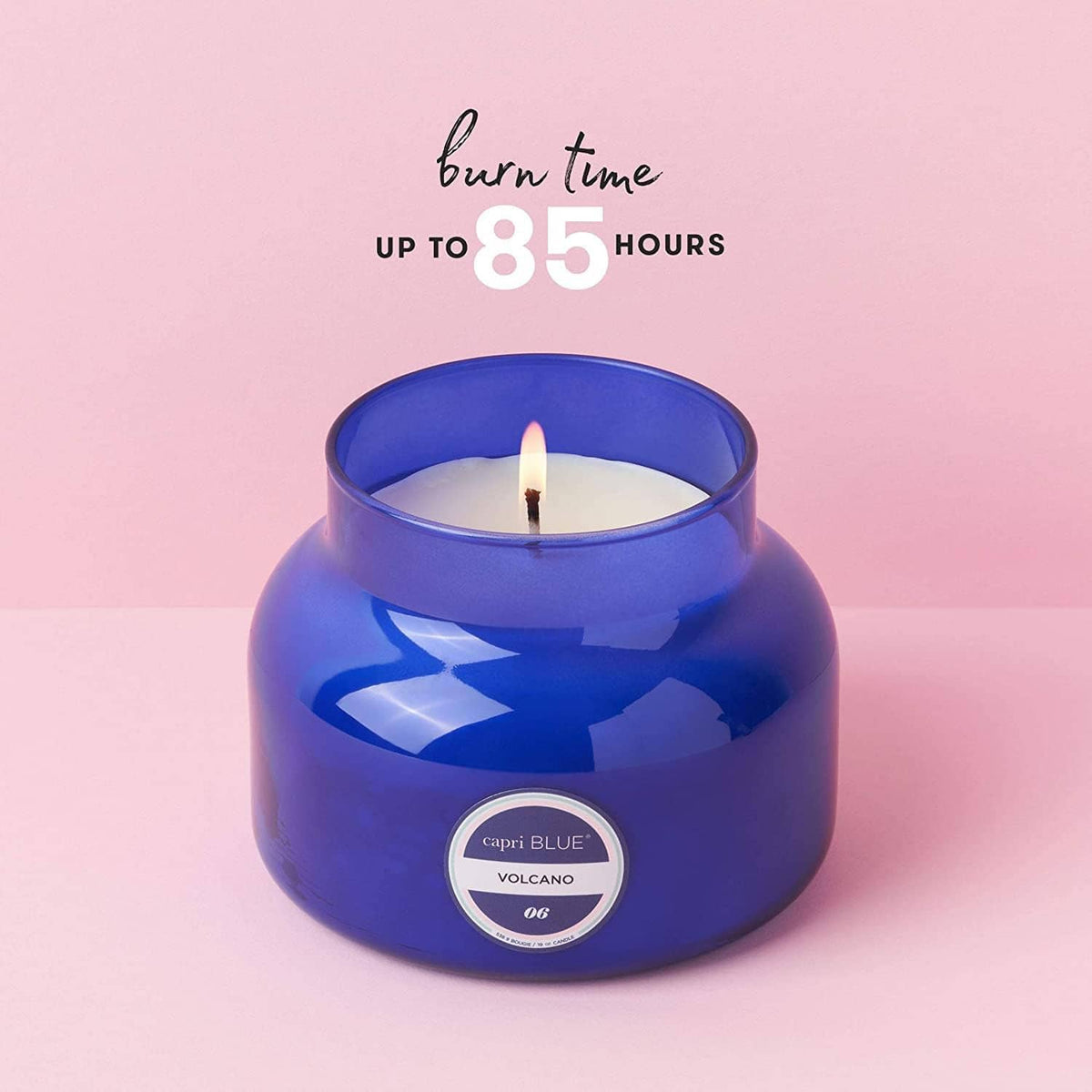 Blue glass jar candle with steady flame and round label on glossy jar