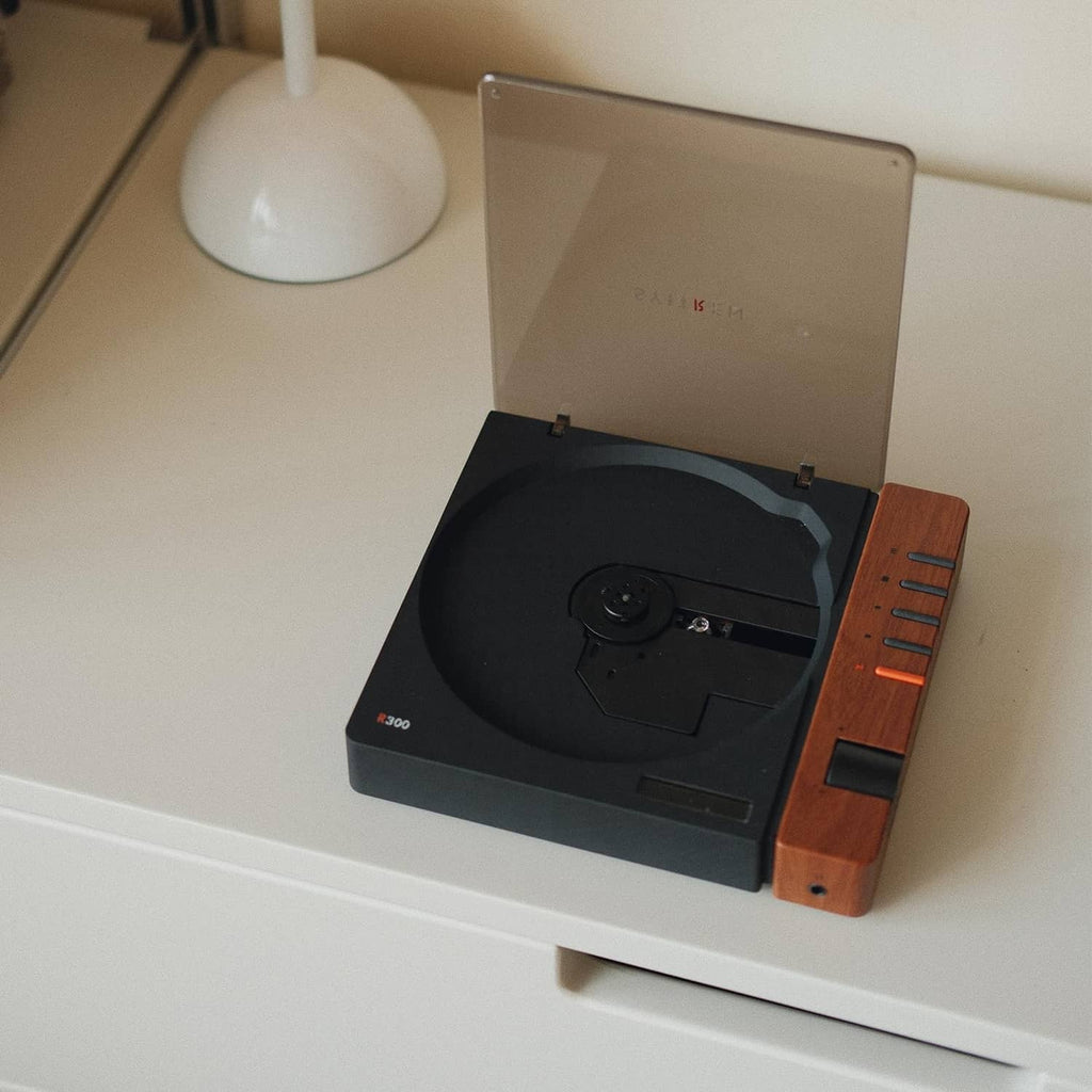 Portable retro CD player on tabletop with open lid, black disc tray and wood trim