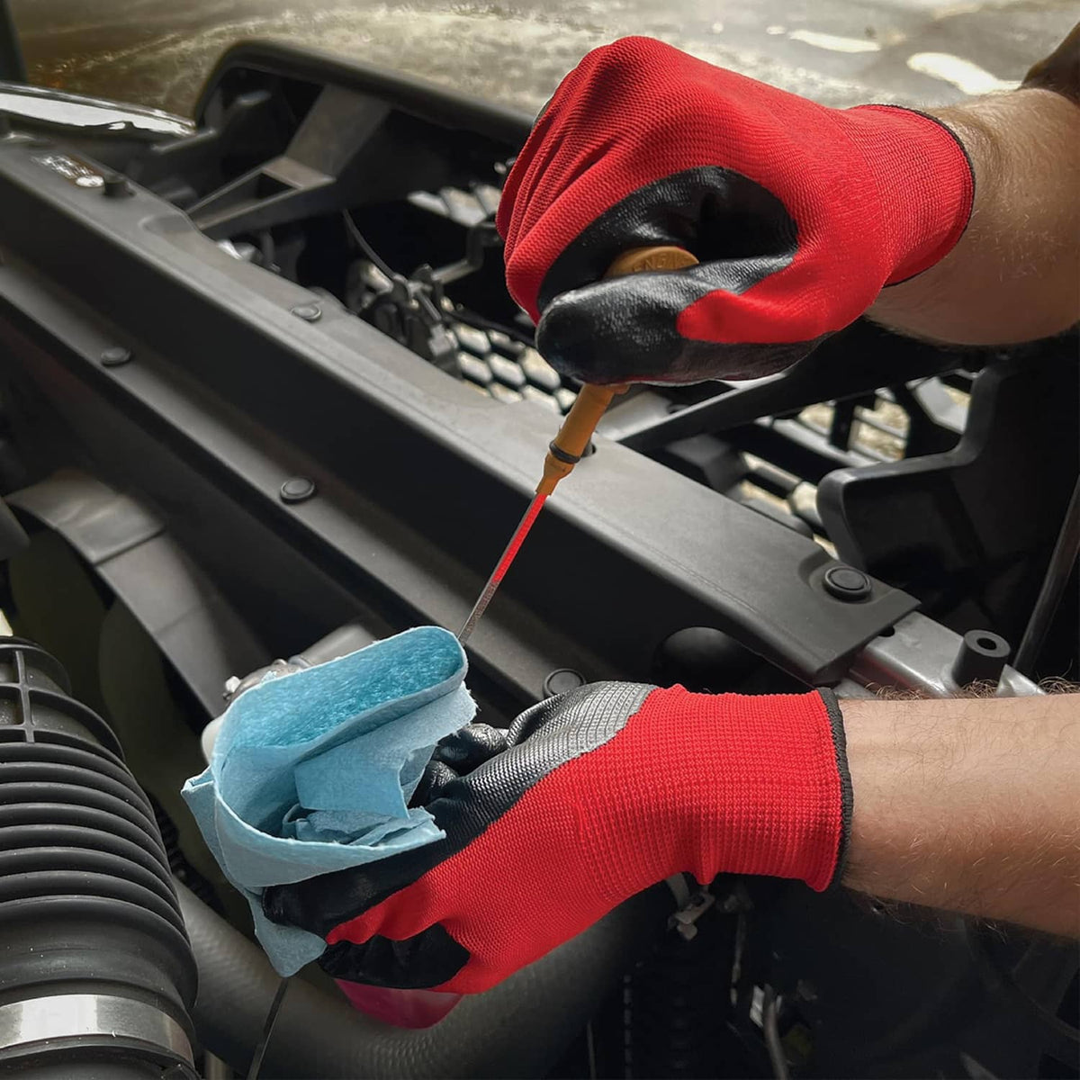 Orange and black nitrile-coated work glove using a screwdriver in an engine bay