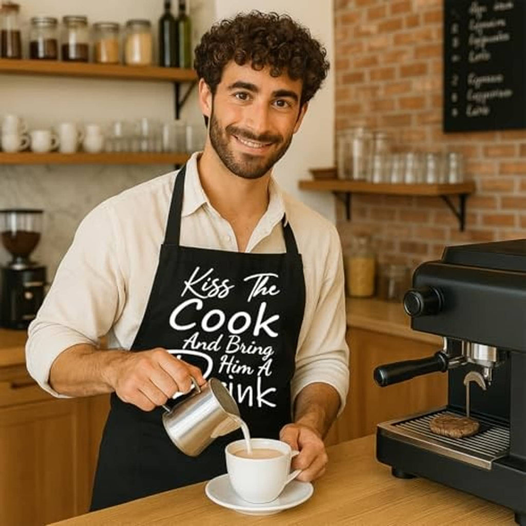 Black adjustable cooking apron with “Kiss The Cook” text while holding a shaker