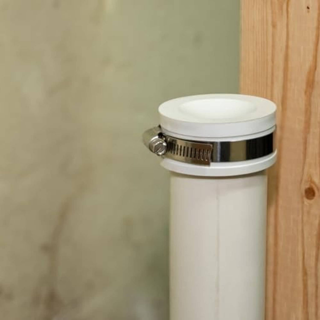 White flexible PVC pipe cap with clear top and stainless clamp band on a pipe