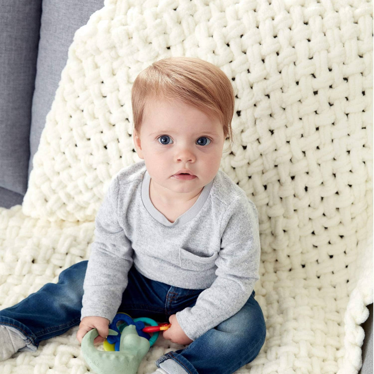 Cream chunky knit blanket with baby seated on it