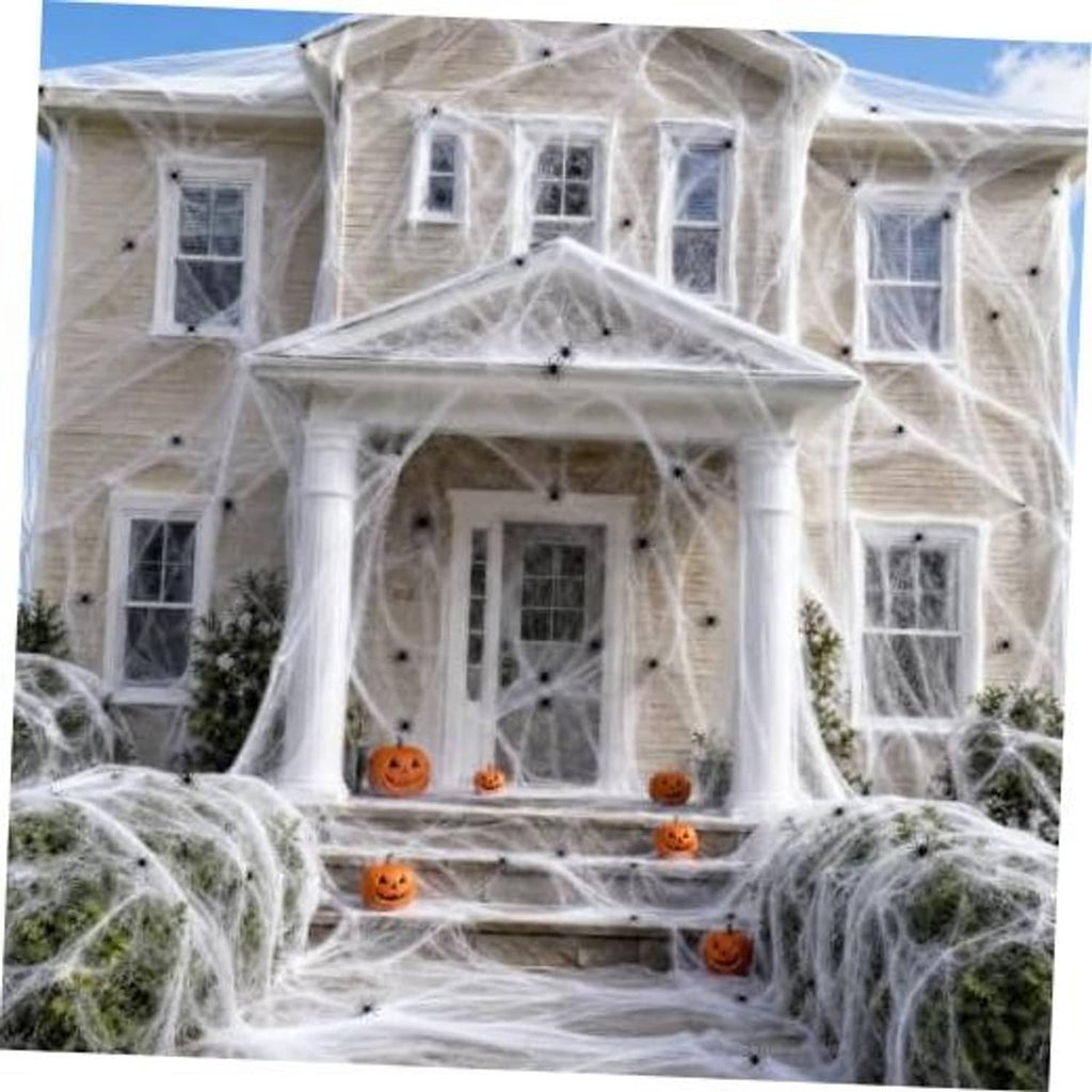 White fabric spider webbing draped over a house facade with orange jack-o-lanterns