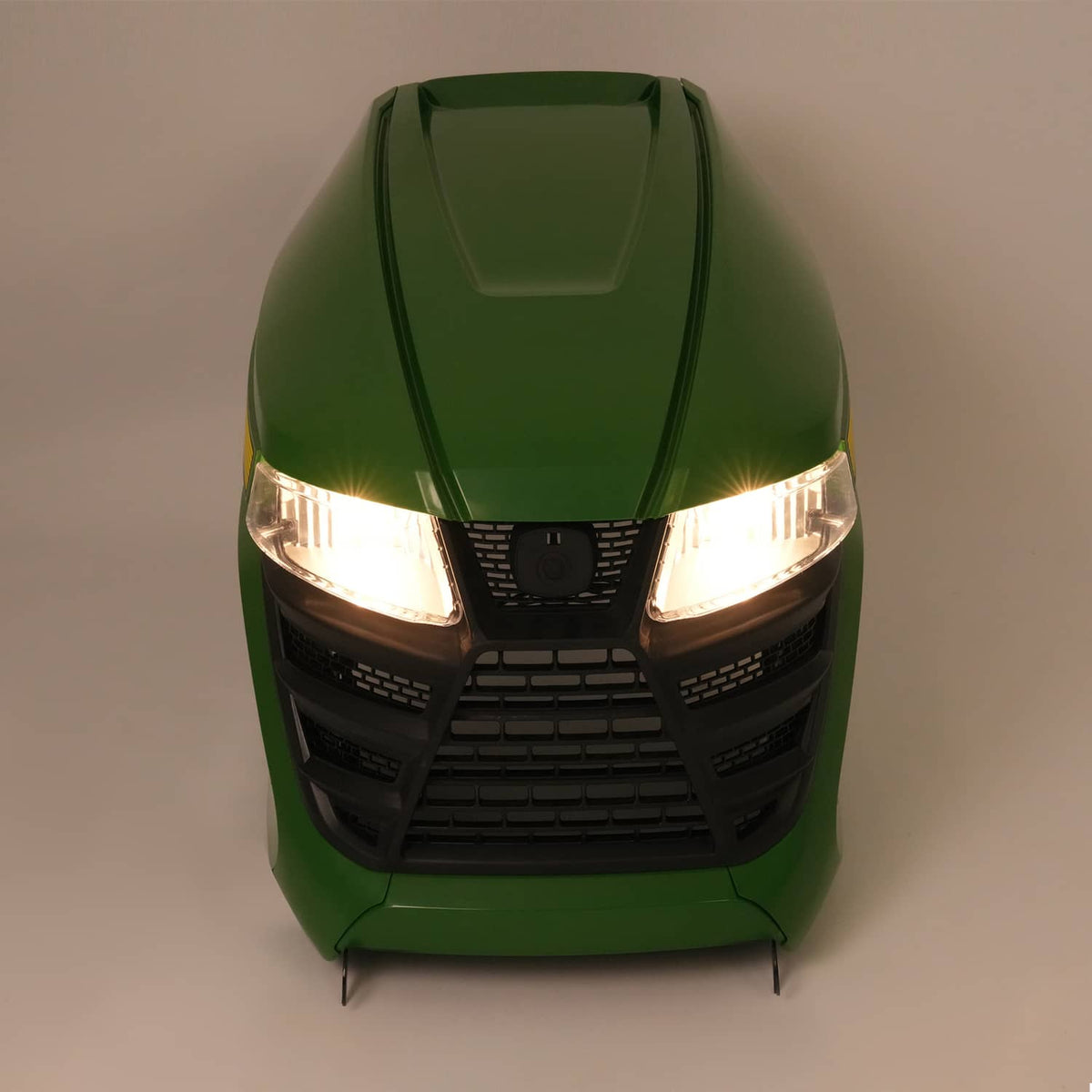 Green lawn tractor front with illuminated headlights and black grille panel