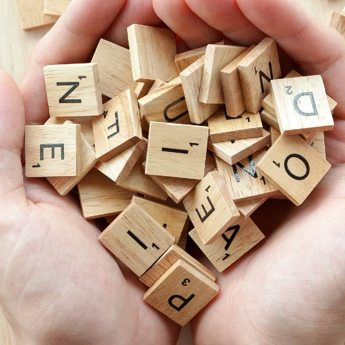 Handful of QMET wood letter tiles with dark printed letters, natural light woodgrain