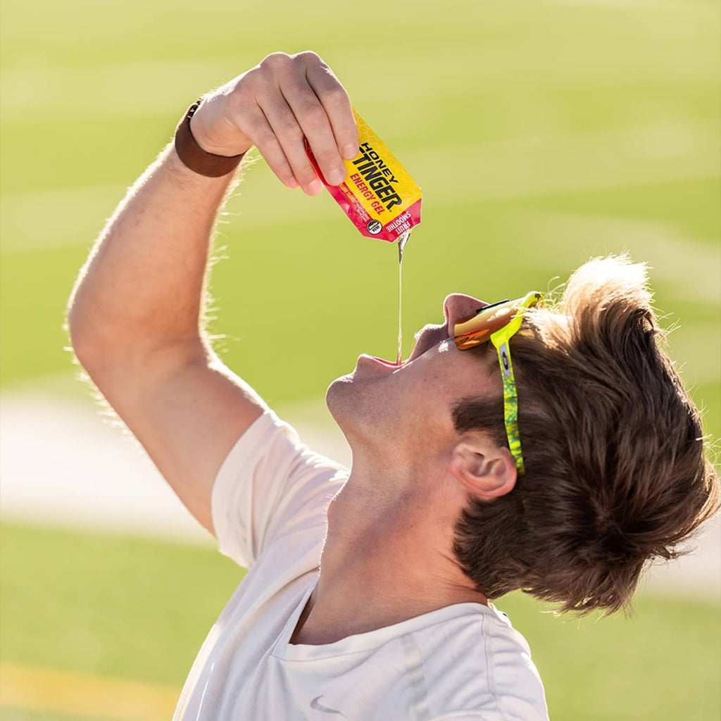 Athlete holding Honey Stinger organic fruit smoothie energy gel packet above mouth