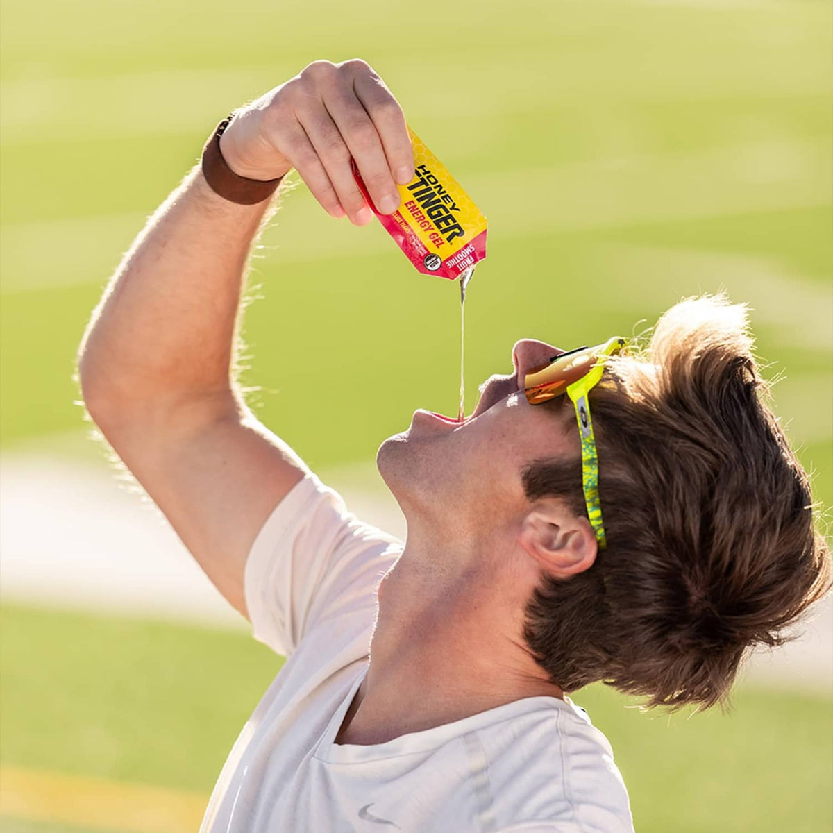 Athlete holding Honey Stinger organic fruit smoothie energy gel packet above mouth