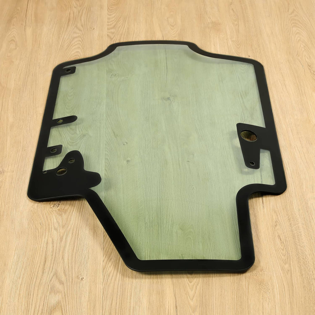 Skid steer door glass panel with black frame and bracket tabs, light blue tint