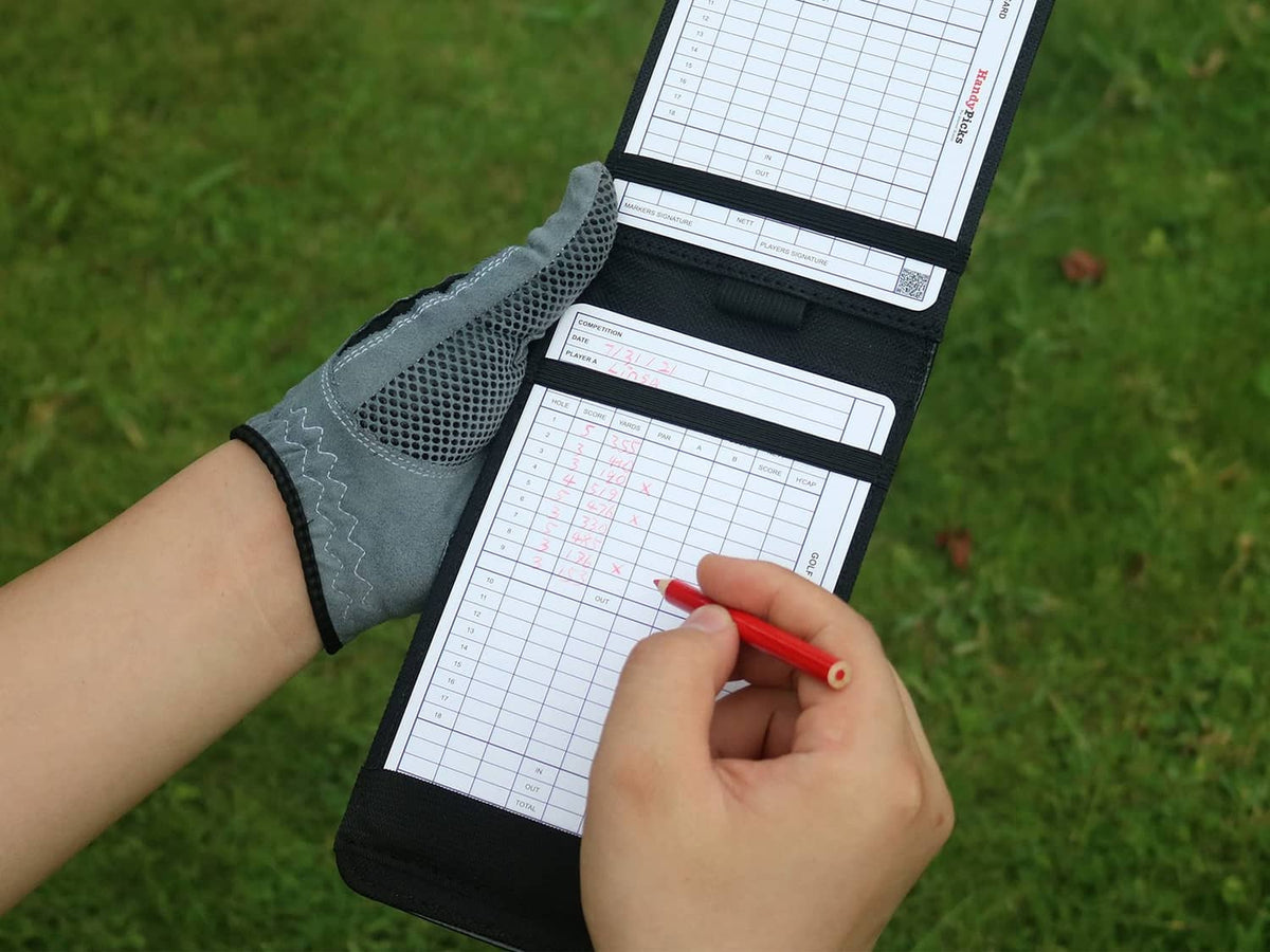 Black leather golf scorecard holder opened flat with scorecard pages and pen
